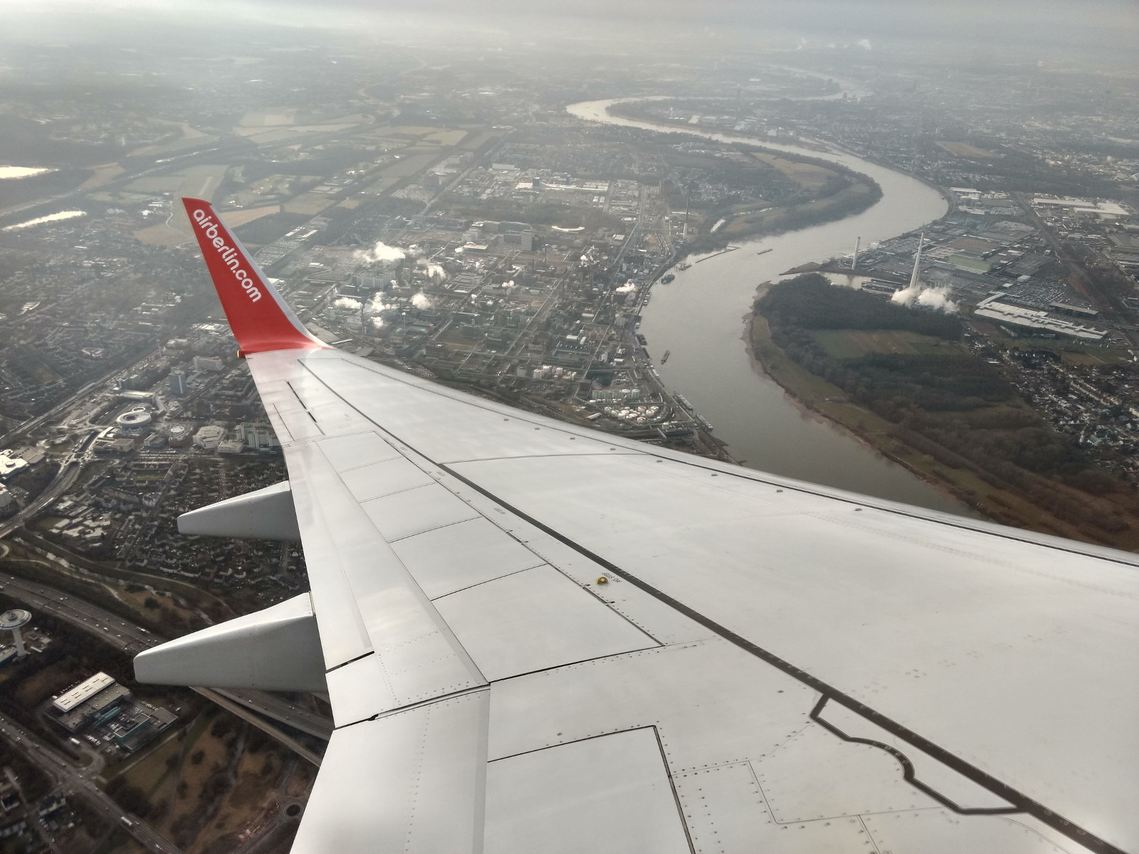 A photo of cologne out of an airplane with the wing of the plane